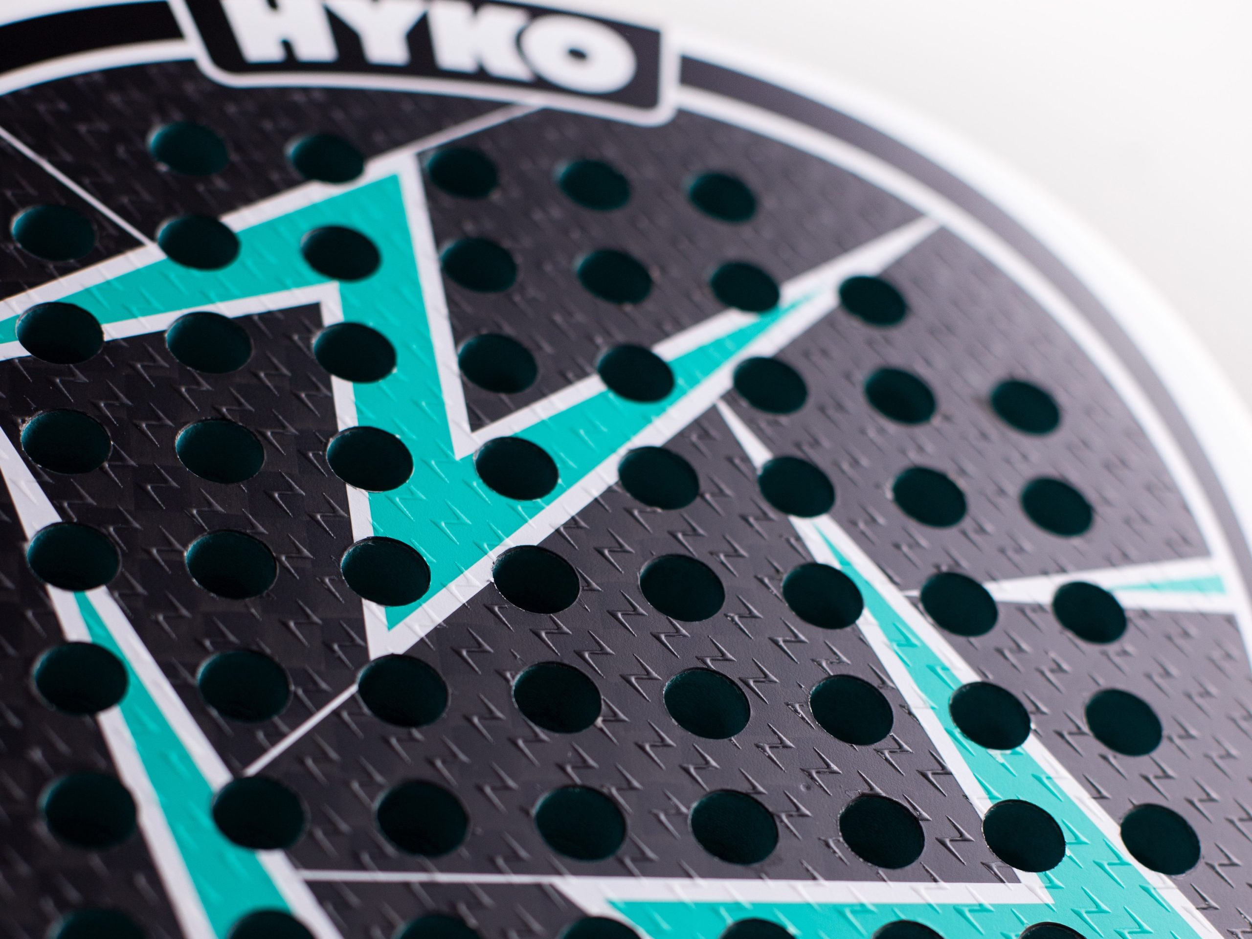 Close-up of a teal and black perforated game board segment with white borders and round teal holes.